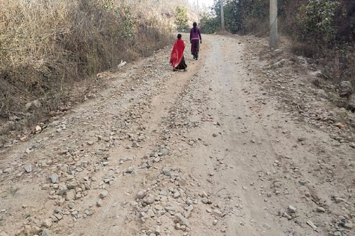 जर्जर सड़क से गुजरते स्थानीय लोग