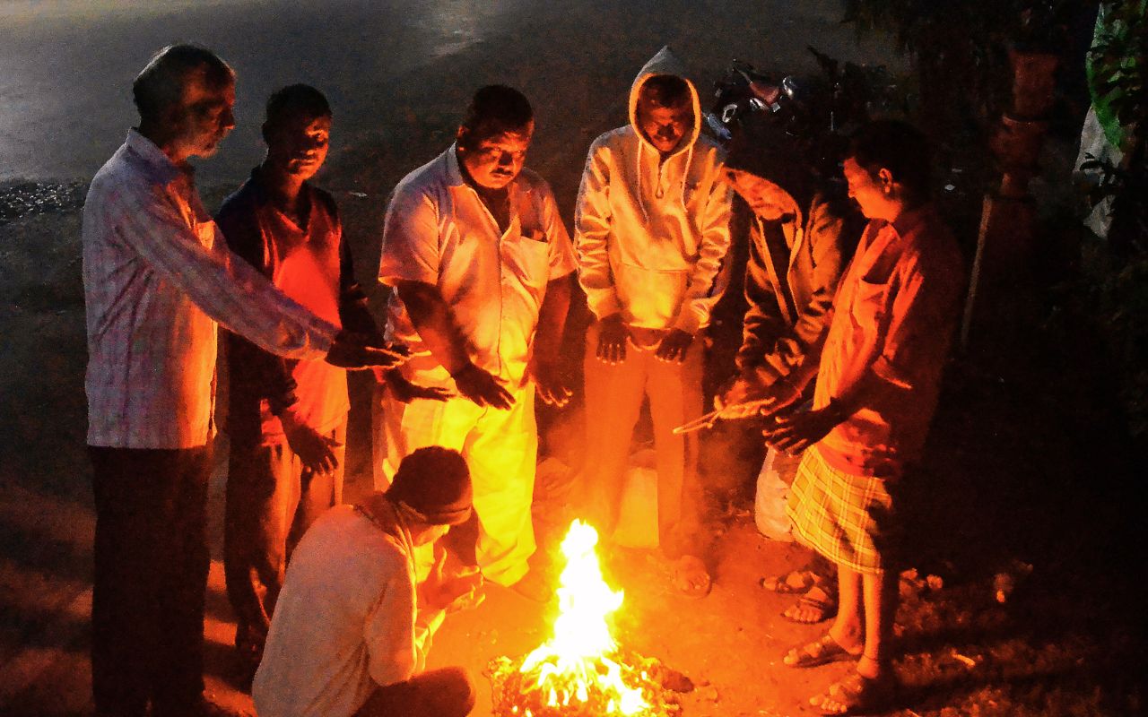 ठंड से बचने के लिए अलाव ताप रहे लोग
