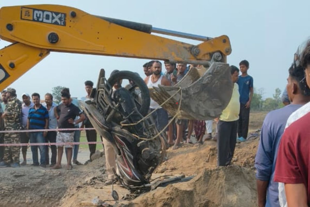 घटनास्थल पर मौजूद लोगों की भीड़ और जेसीबी की मदद से बाइक को बाहर निकालते हुए