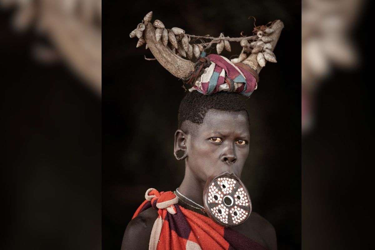 अपने होठों में प्लेट लगाए मुर्सी जनजाति की एक महिला. 