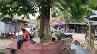 बादलों के बावजूद राहत नहीं: कमतौल बाजार में दोपहर को पसरा सन्नाटा, पेड़ की छांव में ले रहे राहत
